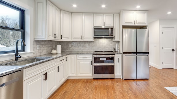 A modern kitchen with white cabinetry, stainless steel appliances, and a wooden floor. - 2 Mi to Lake Tomahawk Park! Quiet Escape w/ Deck (Black Mountain)