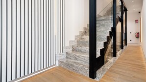 A modern interior with a marble staircase, wooden flooring, and a glass railing. - Dobo Madrid Betanzos (Madrid)