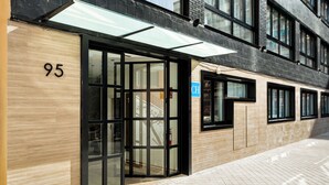A building with a large glass door entrance, a wooden facade, and a blue sign with the letter "CH". - Dobo Madrid Betanzos (Madrid)
