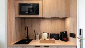 A compact kitchen with a black microwave, a coffee maker, a kettle, and a small sink. - Dobo Madrid Betanzos (Madrid)