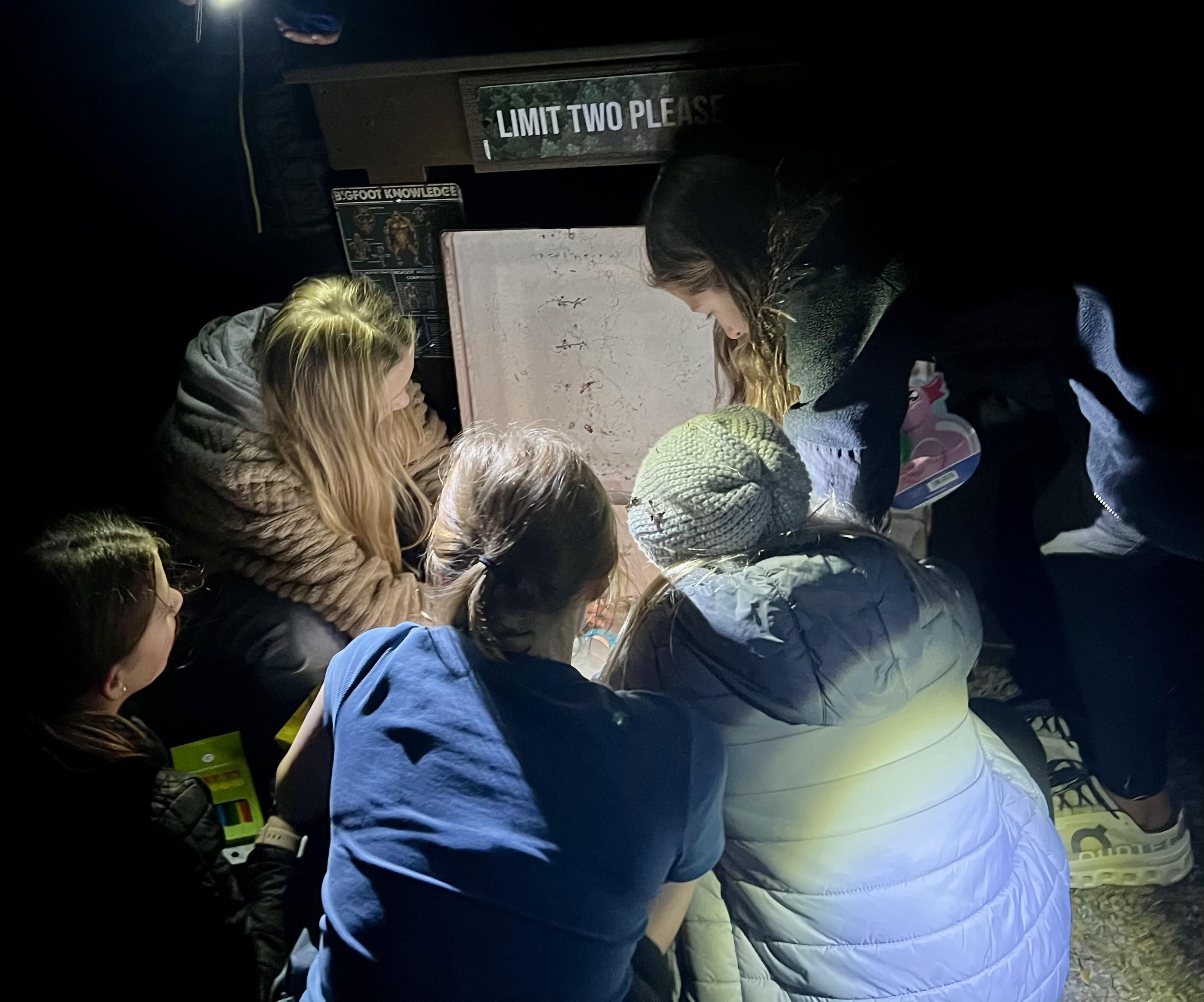 A group of people gathered around a display with a sign that reads "LIMIT TWO PLEASE."