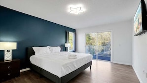Ein Schlafzimmer mit Bett, Nachttisch und Blick auf einen Balkon.
