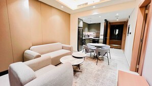 A modern living room with a sofa set, a round coffee table, and a dining area with chairs. - Luxury Living at Cloud Tower JVT with  (Dubai)