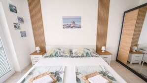 A bedroom with a bed, two nightstands, a mirror, and a wall with pictures. - Spacious 1 bedroom apartment in charming Supetarska Draga with AC (Supetarska Draga)