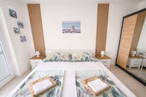 Ein Schlafzimmer mit einem Bett, zwei Nachttischen, einem Spiegel und einer Bilderwand.