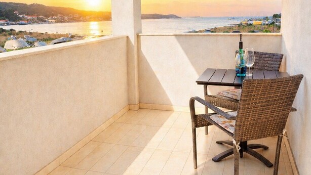 A balcony with a view of the sunset over the sea, a table with chairs, and a bottle of wine. - Spacious 1 bedroom apartment in charming Supetarska Draga with AC (Supetarska Draga)