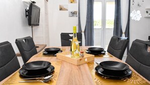 A dining table set with black plates, a bottle of wine, and a wooden tray with glasses. - Spacious 1 bedroom apartment in charming Supetarska Draga with AC (Supetarska Draga)