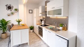 A modern kitchen with white cabinetry, a wooden countertop, and a built-in oven. - Spacious 1 bedroom apartment in charming Supetarska Draga with AC (Supetarska Draga)