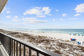 A beach view from a balcony with a railing, sandy beach, and ocean. - SD 405: Emerald Beach Hide Away (Ft Walton Beach)