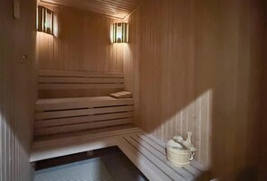 A sauna with wooden benches and a small table with a towel and a container. - Luxury 1BR LIV Marina Modern With Marina View (Dubai)