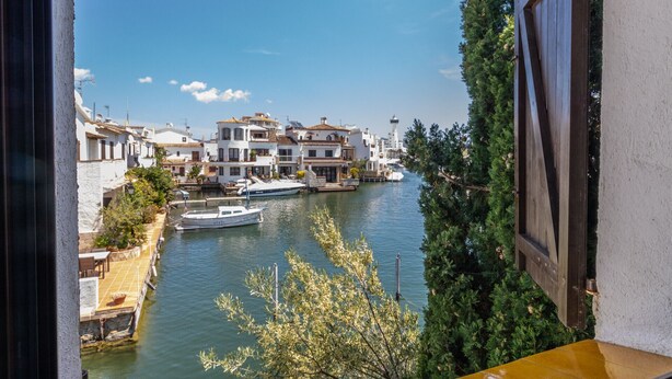 Un canal con edificios y barcos, visto desde un balcón.