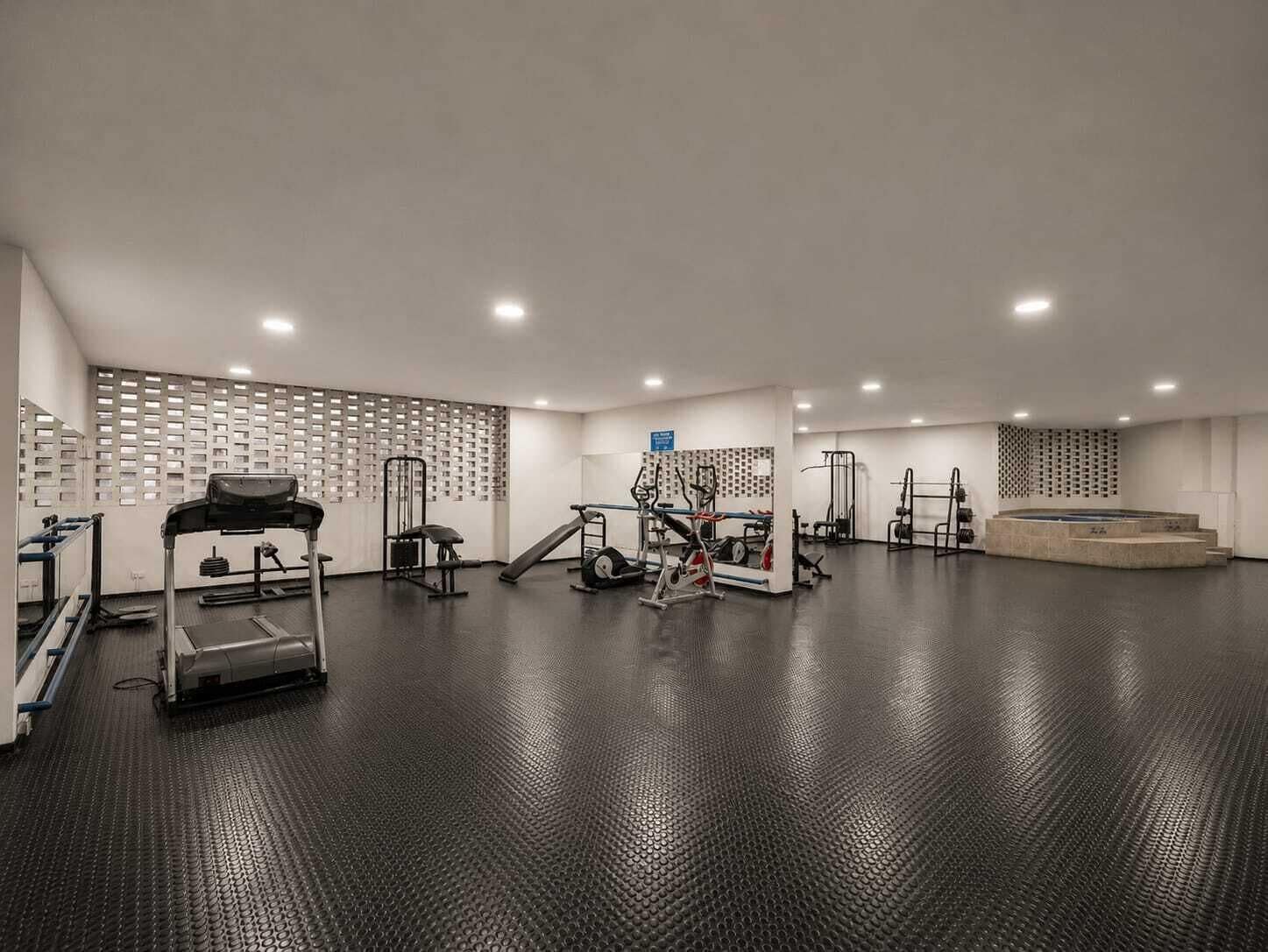 Ein Fitnessstudio mit Laufbändern, Kraftgeräten und einem Poolbereich.