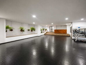 A spacious indoor area with a reception desk, a staircase, and exercise equipment.