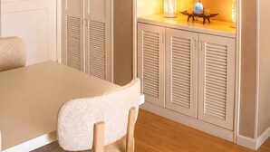 A room with a dining table, chairs, a cabinet with shelves, and a hanging light fixture. - Luxury Apartment in Cali's Zona Rosa—Terrazas de Granada (Cali)