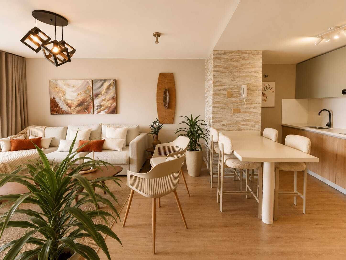 A modern living room with a sofa, chairs, a dining table, and a kitchen area.