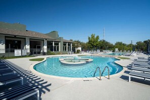 A swimming pool with lounge chairs and a building with a covered patio. - Gateway Denton (Denton)