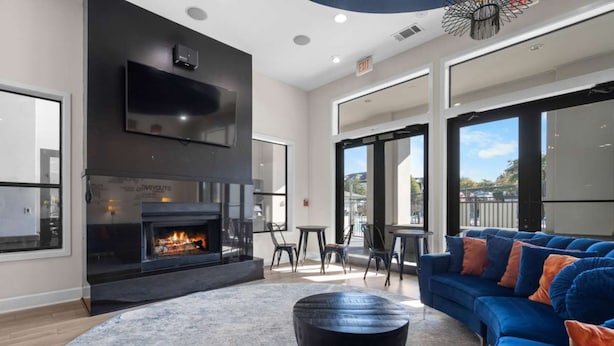 A modern living room with a fireplace, a blue sofa, and a round coffee table. - Gateway Denton (Denton)