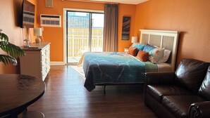 Een hotelkamer met een bed, een leren bank, een bureau met een lamp en uitzicht buiten door een schuifdeur.