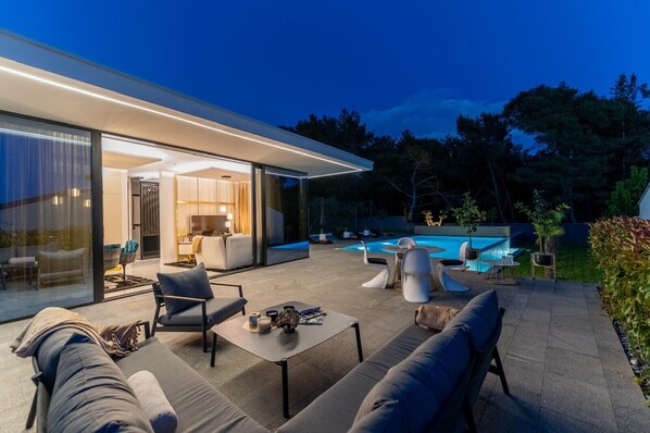 A modern house with a glass-enclosed patio, a swimming pool, and outdoor furniture. - Villa Matoš Estate Zadarvillas (Zadar)