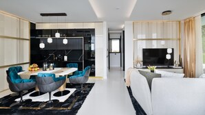 Un salon moderne avec un canapé, un téléviseur et un coin repas comprenant des chaises et une table.