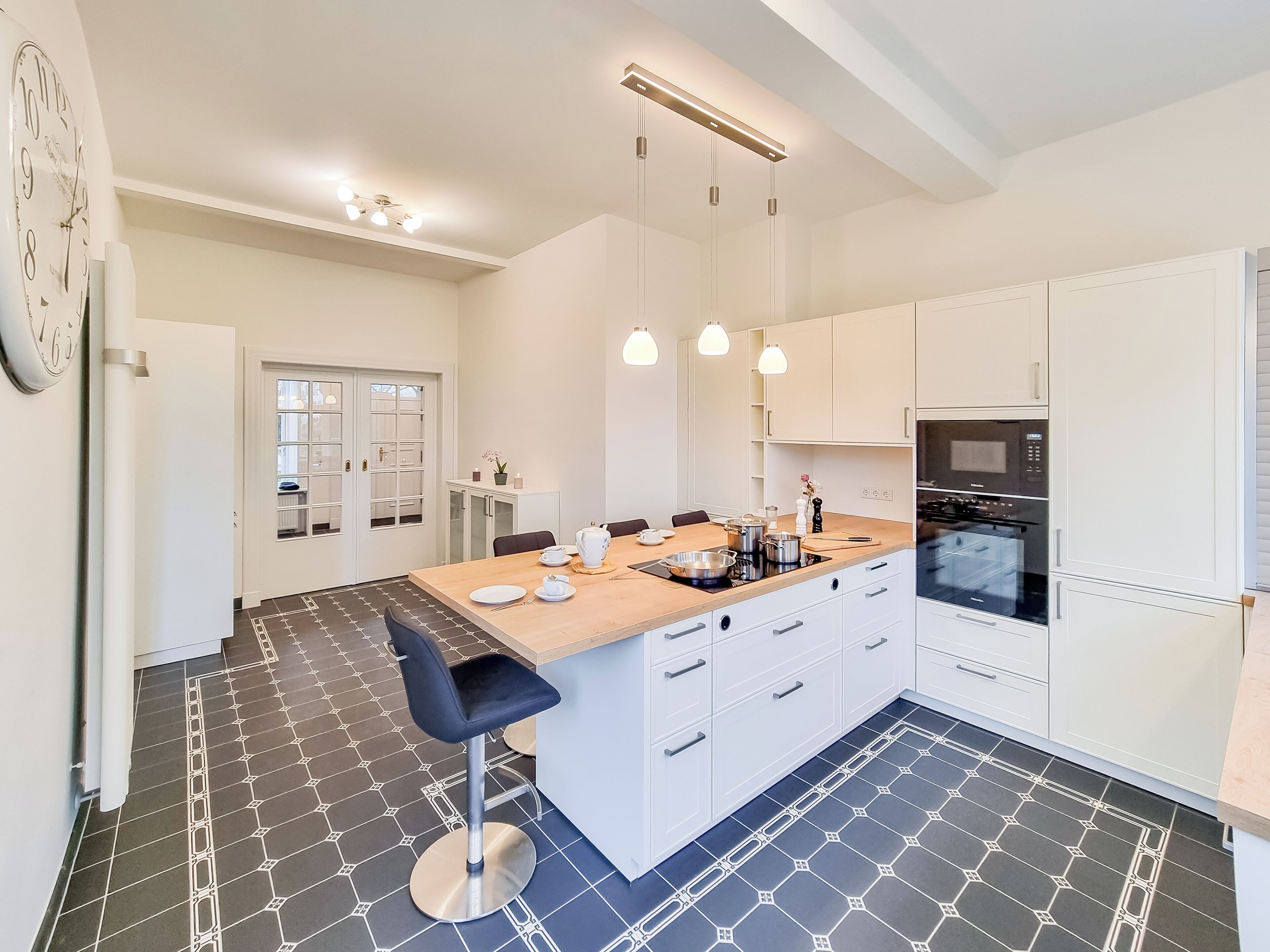 A modern kitchen with a central island, white cabinetry, and a patterned floor.