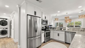A modern kitchen with stainless steel appliances, white cabinetry, and a round rug. - Updated 3-Bedroom Condo! Near Beach, Baytowne, Pool, Shopping & Entertainment (Miramar Beach)