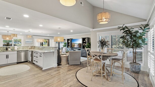 A spacious kitchen with wooden flooring, white cabinetry, and a dining area with wicker chairs and a round table. - Updated 3-Bedroom Condo! Near Beach, Baytowne, Pool, Shopping & Entertainment (Miramar Beach)