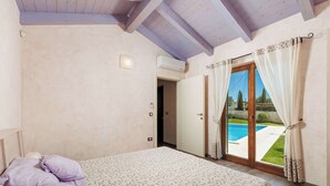 Ein Schlafzimmer mit einem Bett, einer Tür zu einem Balkon und einer Klimaanlage.