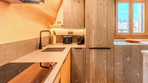 A modern kitchen with a built-in stove, a coffee maker, and wooden cabinetry.