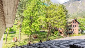 A mountain view with a wooden deck, a swing set, and a building with a sloped roof.
