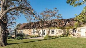 A stone building with a sloped roof, surrounded by a well-maintained lawn and trees. - Hameau du Dropt - Périgord - sleeps 6 to 33 (Plaisance)