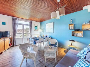 A living room with a wooden ceiling, a dining area with a table and chairs, a sofa, and a television. - Charme de La Linière by Interhome (Ile de Noirmoutier)