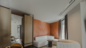 Ein modernes Hotelzimmer mit einer Couch, einem runden Tisch und einem großen Fenster.
