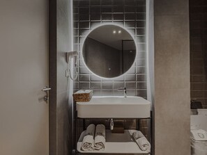 A bathroom with a white sink, a round mirror, and a towel rack with towels. - Zins Luxury Room 01 in Durr s (Durrës)