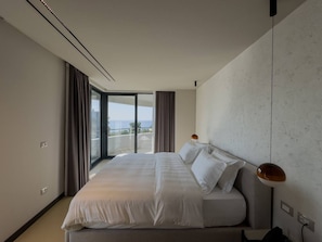 A modern hotel room with a large bed, a view of the sea through floor-to-ceiling windows, and a minimalist design. - Zins Luxury Room 01 in Durr s (Durrës)