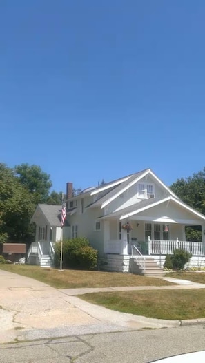 A single-story house with a front porch, a chimney, and a flag.