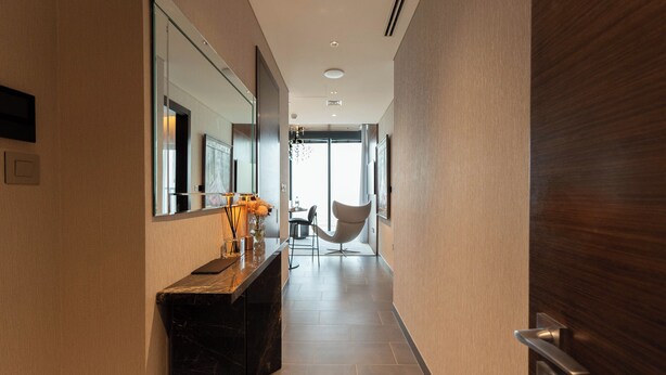 A modern hallway with a marble counter, a chair, and a door. - Luxury 1BR High-Floor Retreat (Dubai)