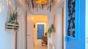 Un couloir avec un luminaire suspendu, une porte bleue et un tapis à motifs.