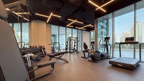 Ein Fitnessstudio mit unterschiedlichen Trainingsgeräten, großen Fenstern und Blick auf die Stadtlandschaft.
