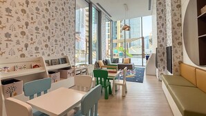 Ein Spielzimmer für Kinder mit großem Fenster, einer Couch und einem Bücherregal.
