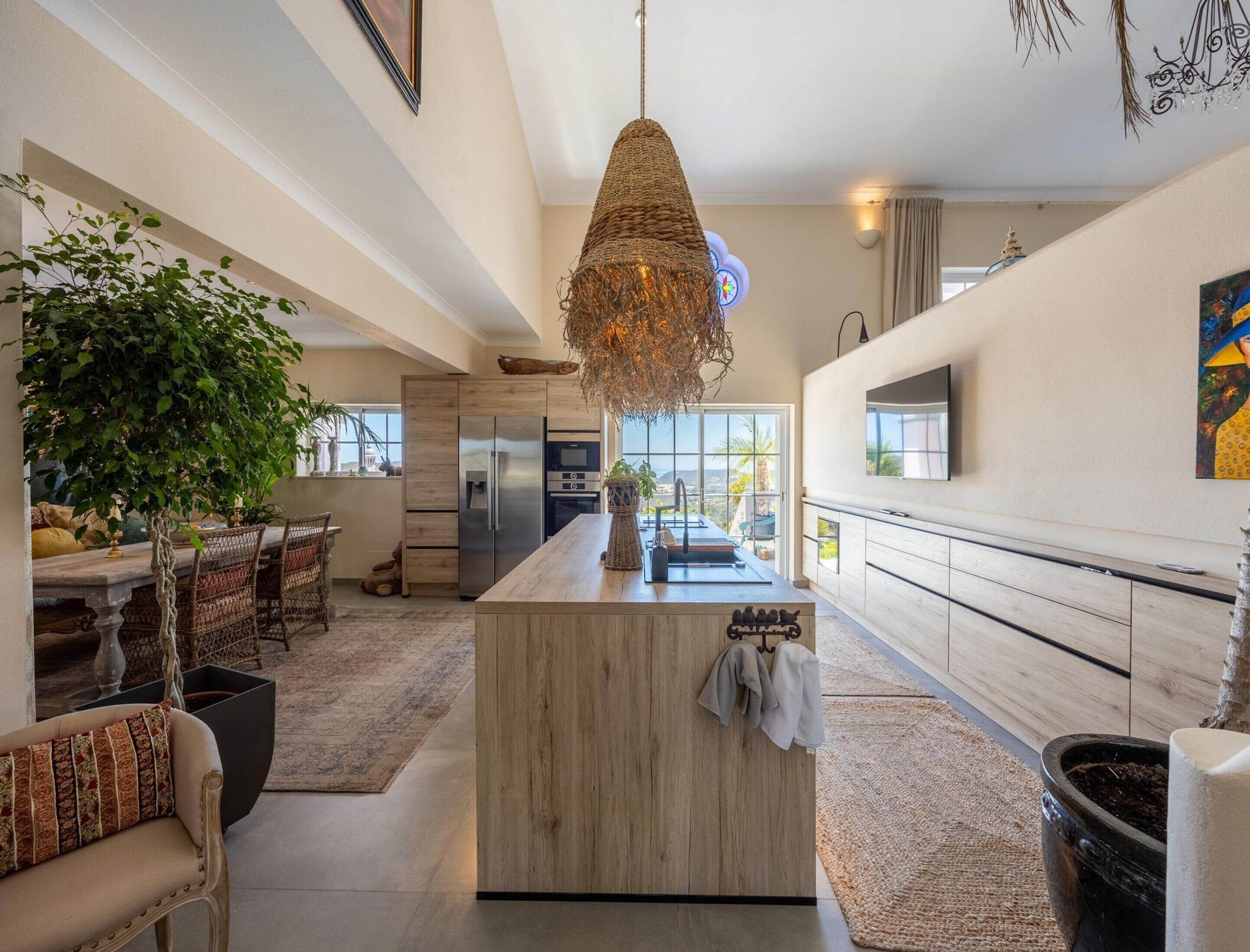 Una cocina amplia con una isla central, una lámpara colgante y vistas al exterior.