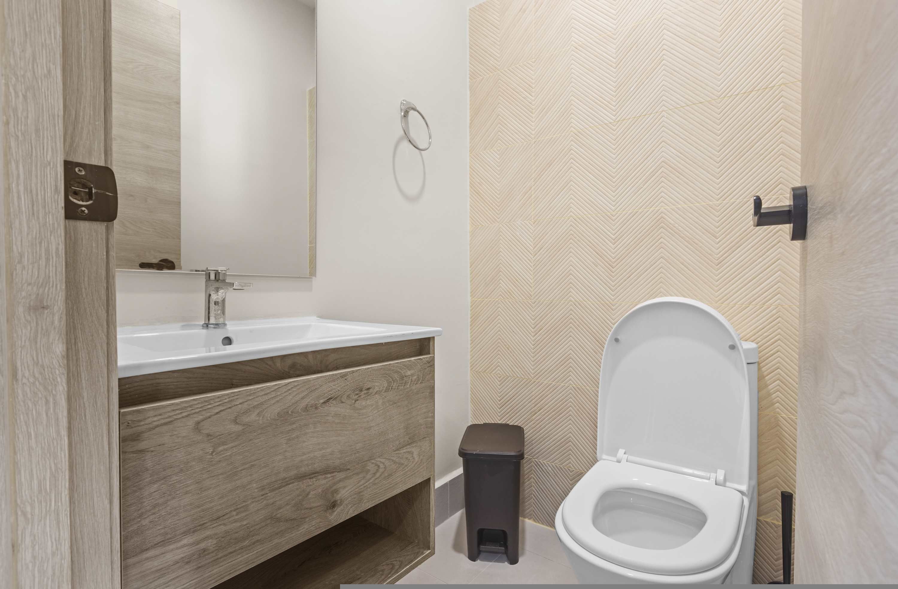 Un bagno moderno con un mobile bagno in legno, un water e uno specchio.