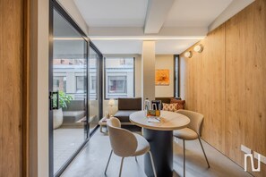 A modern interior with a round table, two chairs, a sofa, and a glass partition. - NOK Designer Apartment 1BR in Zona Rosa (Bogotá)
