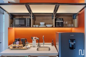 A compact kitchen with a microwave, coffee maker, and a water dispenser. - NOK Designer Apartment 1BR in Zona Rosa (Bogotá)
