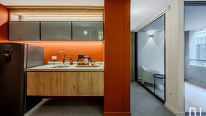 A modern kitchen with a built-in refrigerator, wooden cabinets, and a countertop with a coffee maker. - NOK Luxury 1BR Apartment With Private Terrace (Bogotá)