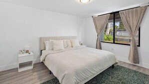 A bedroom with a bed, nightstand, and window with curtains. - Miami Hotel Home + jacuzzi+sauna +barbecue (Miami)