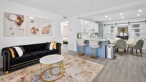 A modern living room with a black sofa, a round gold table, and a marble-patterned rug. - Miami Hotel Home + jacuzzi+sauna +barbecue (Miami)