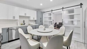 A modern kitchen with white cabinets, a central island with seating, and a sliding glass door closet. - Miami Hotel Home + jacuzzi+sauna +barbecue (Miami)