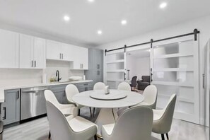 A modern kitchen with white cabinets, a central island with seating, and a sliding glass door closet. - Miami Hotel Home + jacuzzi+sauna +barbecue (Miami)