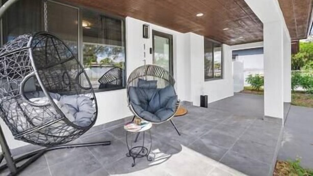 A covered outdoor seating area with two chairs, a small table, and a view of the outdoors. - Miami Hotel Home + jacuzzi+sauna +barbecue (Miami)